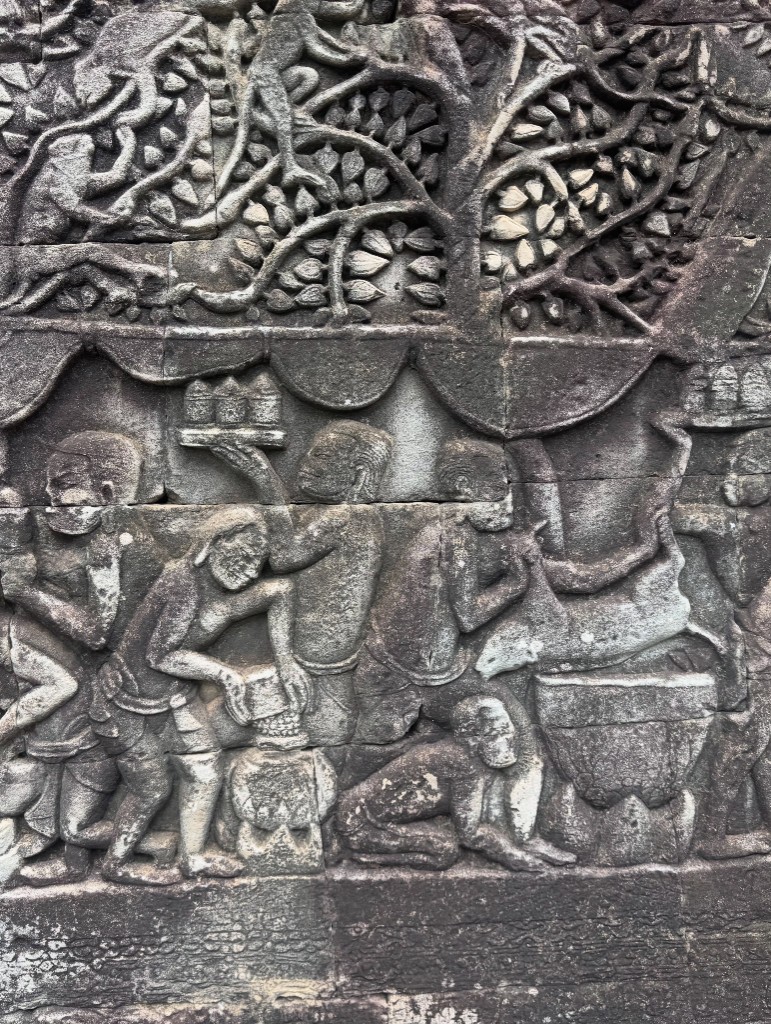 A relief panel showing a line of servants carrying trays, carved beneath a tree canopy