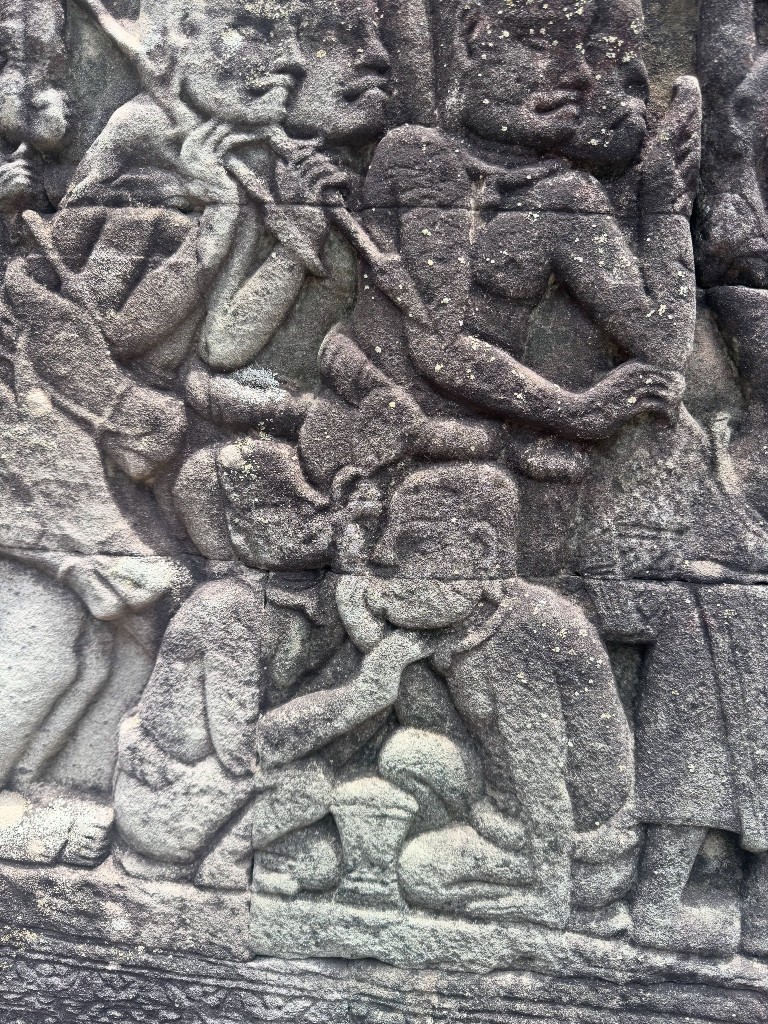 A close up bas-relief of figures gathered together, one drawing on a pipe