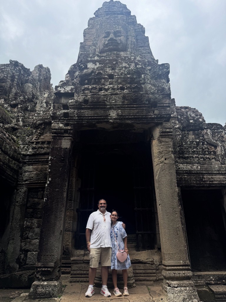 My daughter and I standing beneath one of the Bayon face towers in a doorway connecting the outer gallery to the interior