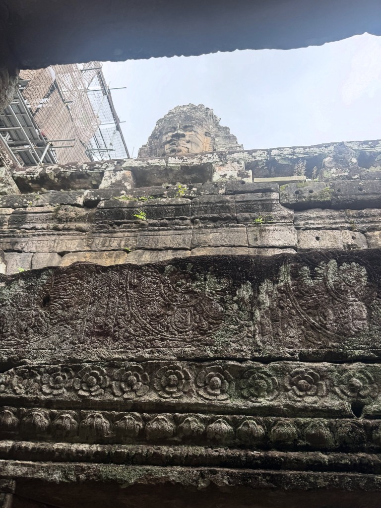 One of the Bayon faces spotted above a gallery wall, a band of floral carving running beneath it