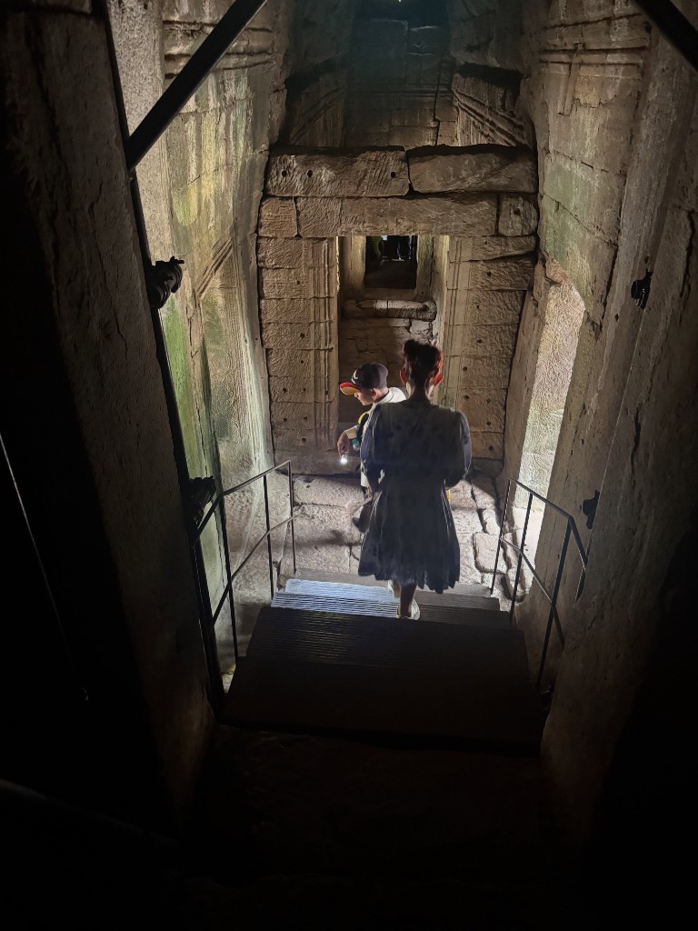 Descending a narrow interior stairway inside Bayon, another visitor and our guide ahead