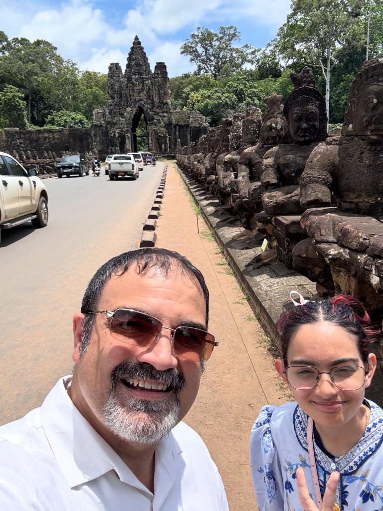 My daughter and I taking a selfie on the causeway, the row of devas beside us and the gate in the background